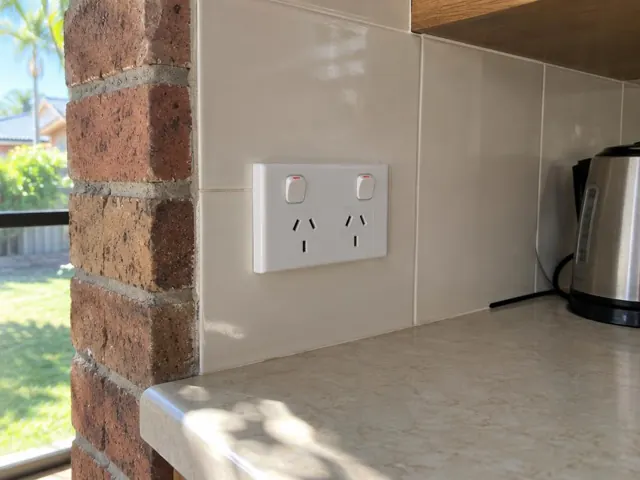 Double power point fitted in a tiled kitchen splashback beside a brick wall in Labrador
