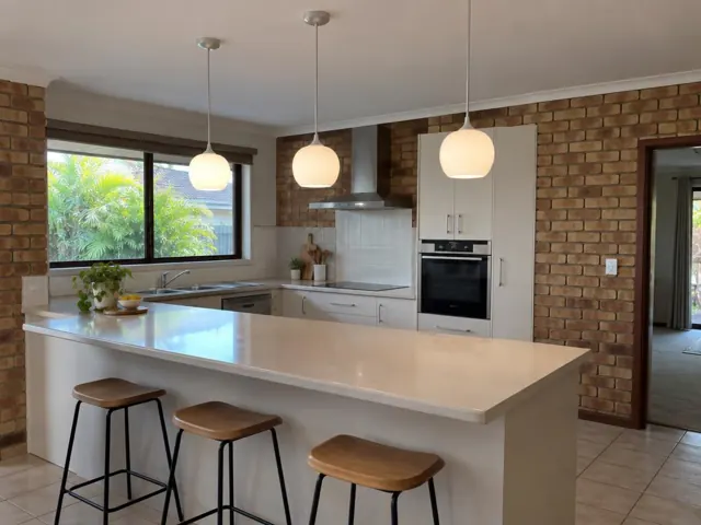 Three pendant lights over a kitchen island in a brick home kitchen in Labrador