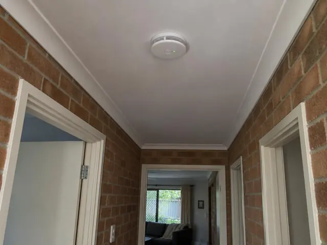 Ceiling smoke alarm in a brick hallway with white trim in Southport